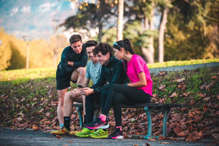 Läufer schauen sich die RunMotion Coach App auf dem Handy an