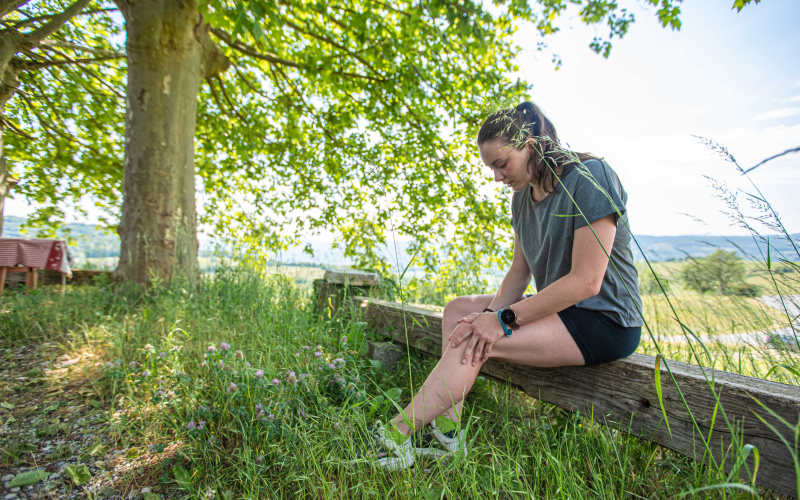 Lauferin mit Kniebandage pausiert nach Laufverletzung und plant sichere Ruckkehr ins Lauftraining.