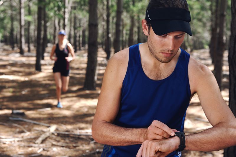 Laeufer nutzt Pulsmesser und GPS Uhr fuer effektives Herzfrequenz Training beim Laufen.