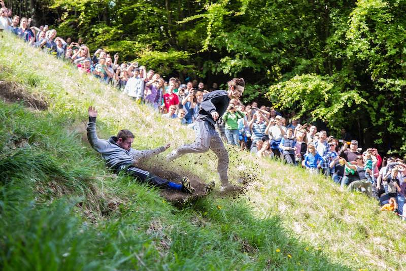 Teilnehmer rennen beim Cooper’s Hill Käserennen bergab und testen ihre Ausdauer im Laufrennen.