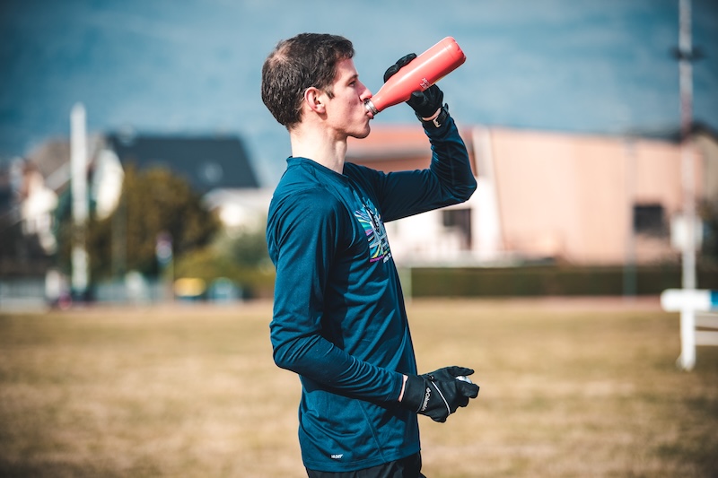 Laeufer nimmt Proteinshake nach dem Lauftraining fuer schnellere Regeneration und staerkere Performance.