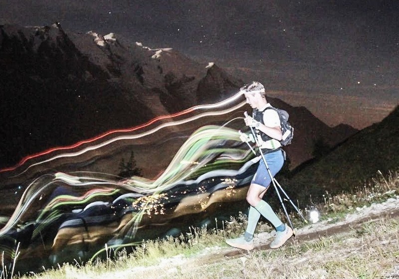 Trailrunner bei Nacht mit Stirnlampe auf Waldtrail, läuft sicher und stark ins Ziel.
